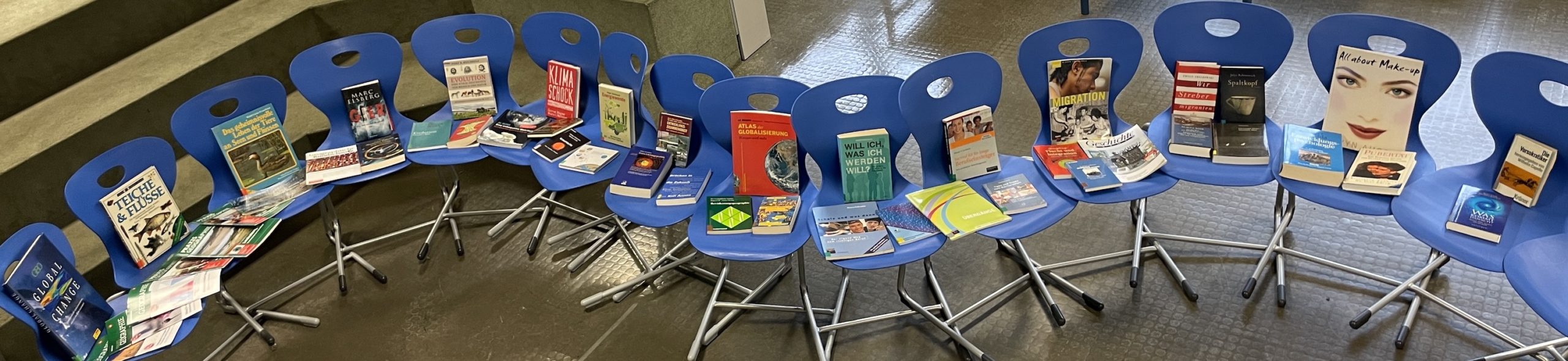 Das Foto zeigt Bücher zum Thema Veränderung auf einem Fluss aus blauen Stühlen.